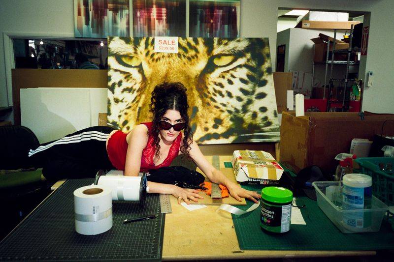 Image may contain: Kate Berlant, Face, Head, Person, Photography, Portrait, Furniture, Table, Accessories, Glasses, and Adult